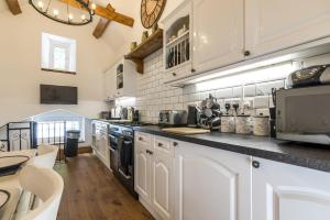 a kitchen with white cabinets and a counter top at The Coach House - 3 Bedroom Holiday Home - Penally - Tenby in Penally