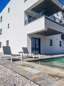 Apartments Antico في تروغير: مبنى يوجد به كرسيين بجانب مسبح