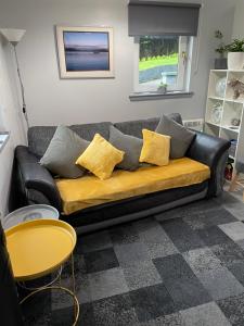 - un canapé noir avec des oreillers jaunes dans le salon dans l'établissement Burnside, à Oban