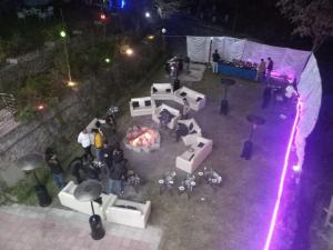 un grupo de personas de pie alrededor de un escenario por la noche en Bhurban View Apartments, en Murree