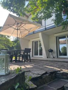 une terrasse avec une table et un parasol en face d'une maison dans l'établissement La Parenthèse gîte à la campagne, à Fougerolles