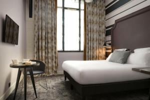 um quarto de hotel com uma cama e uma pequena mesa em Hôtel Fabric em Paris