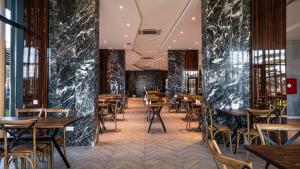- un restaurant avec des tables et des chaises en bois et des murs en marbre noir dans l'établissement Gori Inn, à Gori