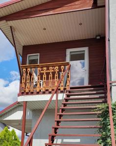 ein Haus mit einem Holzgeländer auf der Veranda in der Unterkunft ŠILAINIŲ APARTAMENTAI in Kaunas