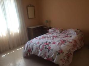 1 dormitorio con 1 cama con colcha de flores y ventana en Mare è Monte , jardin méditerranéen et exotique., en Ghisonaccia