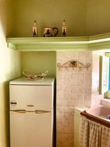 a small kitchen with a white refrigerator and a shelf at Chroma Kastellorizo in Meyisti
