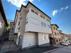 a white house with a garage on a street at Golden Gate Apartment Sarajevo in Sarajevo