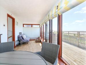 a room with a table and chairs on a balcony at 102 The Beach in Snettisham