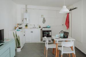 een keuken met witte kasten en een tafel met een laptop bij El garage in Esquel