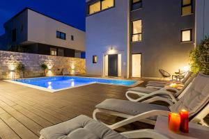 a backyard with a swimming pool and chairs and a building at Villa Luxury HERMES - Heated Pool, Jacuzzi, Elevator in Podstrana