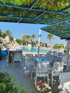 a patio with tables and chairs next to a pool at Hotel Tigaki's Star in Tigaki