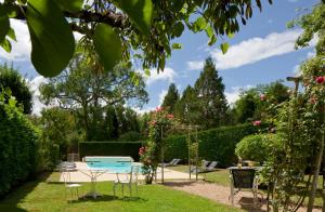 un jardín con mesa, sillas y rosas en Hotel La Roseraie, en Chenonceaux