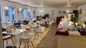 a restaurant with white tables and white chairs at Ferienwohnungen Moenchgut und Ruegen in Lobbe