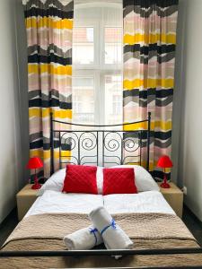 波兹南Expolis Residence - City Center - 24h #betterthanyourEX的一间卧室，有一张带红色枕头的床和一扇窗户