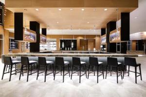 a lobby with a bar with black chairs in it at AC Hotel by Marriott Oklahoma City Bricktown in Oklahoma City