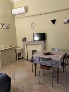 ein Wohnzimmer mit einem Tisch, Stühlen und einem TV in der Unterkunft casa di Carlo e Chiara in Sassari