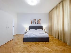 ein Schlafzimmer mit einem Bett sowie Holzböden und -vorhänge in der Unterkunft Elysian Apartment in Bratislava
