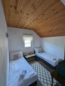 two beds in a room with a wooden ceiling at Holiday Home DMD Sarajevo in Sarajevo