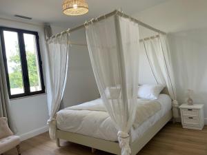 a bedroom with a canopy bed with white curtains at Château de la Busquette - in La Magdelaine-sur-Tarn