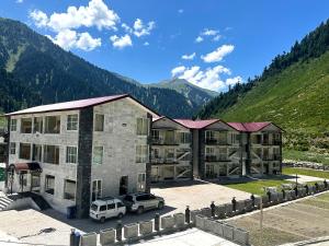 纳兰恩Kunhar Hotel RiverSide Block的一座大楼，停车场里停满了汽车