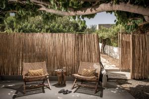 dwa krzesła i stół przed płotem w obiekcie Tarsia Homes & Suites w mieście Kalamaki