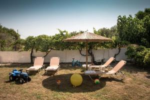 a group of chairs and an umbrella in a yard at Tarsia Homes & Suites in Kalamaki