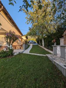 a house with a grass yard with a driveway at Holiday Home DMD Sarajevo in Sarajevo