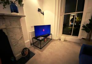 a living room with a tv and a fireplace at Samdel Camden Charles Suite in London