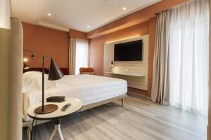 a hotel room with a bed and a desk and a tv at Adesso Hotel in Rome