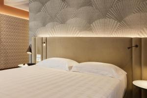 una camera da letto con un grande letto con cuscini bianchi di Adesso Hotel a Roma