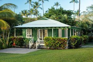 a green house with a porch in a yard at Waimea Plantation Cottages, a Coast Resort in Waimea