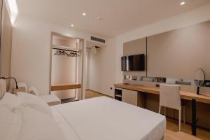 a room with a bed and a desk and a television at JOST Caravel in Vlorë