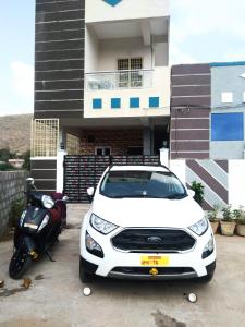 une voiture blanche et une moto garées devant une maison dans l'établissement Duplex house homestay near Vijayawada, Tadepalli, à Vijayawada