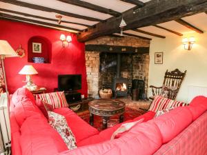een woonkamer met een rode bank en een open haard bij Westgate Cottage in Lapford