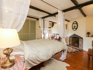 1 dormitorio con cama con dosel y chimenea en Westgate Cottage, en Lapford