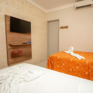 a bedroom with two beds and a flat screen tv at Happy Hotel Brisa do Mar in Ipojuca