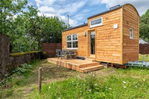 a tiny house with a deck and a table at Enchanting Tiny House with wood burner and hot tub in Cairngorms in Ballater