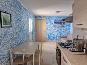 cocina con paredes azules, mesa y sillas en PICCOLA RAFFICA, en Fregene