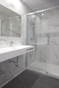 een witte badkamer met een wastafel en een douche bij MANTULENE Apartments - Basque Stay in San Sebastian