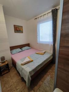 - une petite chambre avec un lit et une fenêtre dans l'établissement Apartman Marija Privlaka, à Privlaka