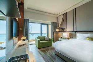 um quarto de hotel com uma cama grande e uma cadeira verde em Amwaj Rotana, Jumeirah Beach - Dubai em Dubai