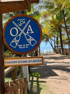 Un cartel en una playa con palmeras y el océano. en Pousada Oceano Atlântico, en Maraú