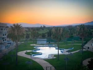 a view of a pool with palm trees and a sunset at Bajo puerta de Alcazaba in Retamar