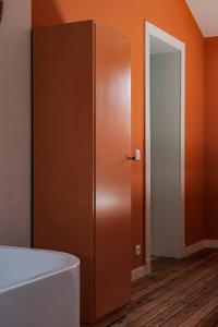 Cette chambre est dotée d'un mur orange et d'une porte. dans l'établissement La Maison du Rivage, à Dinant