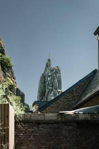 a stone building with a mountain in the background at La Maison du Rivage in Dinant