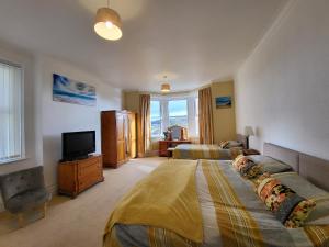 a large bedroom with two beds and a television at Tan Tabin in Llandudno