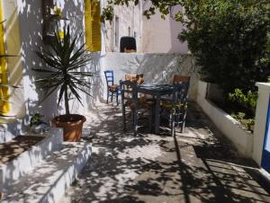 a patio with a table and chairs and a plant at Artist Rooms - Triantafyllou Birth House in Kefalos