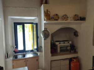a kitchen with a sink and a stove and a window at Artist Rooms - Triantafyllou Birth House in Kefalos