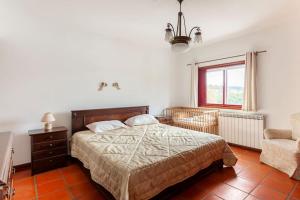 um quarto com uma cama, uma cadeira e uma janela em Maison avec piscine : quinta do sol em Amarante