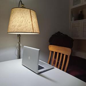 un ordenador portátil sentado en una mesa blanca con una lámpara en DepArt en Rambla Punta Carretas, en Montevideo
